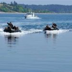 Sailors with the Royal Canadian Navy navigate rigid hull inflatable boats carrying soldiers from the Royal 22e Régiment, to conduct a beach landing exercise near CFB Esquimalt during Exercise Trident Fury.