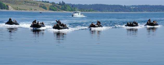Sailors with the Royal Canadian Navy navigate rigid hull inflatable boats carrying soldiers from the Royal 22e Régiment boats carry soldiers ashore during Trident Fury