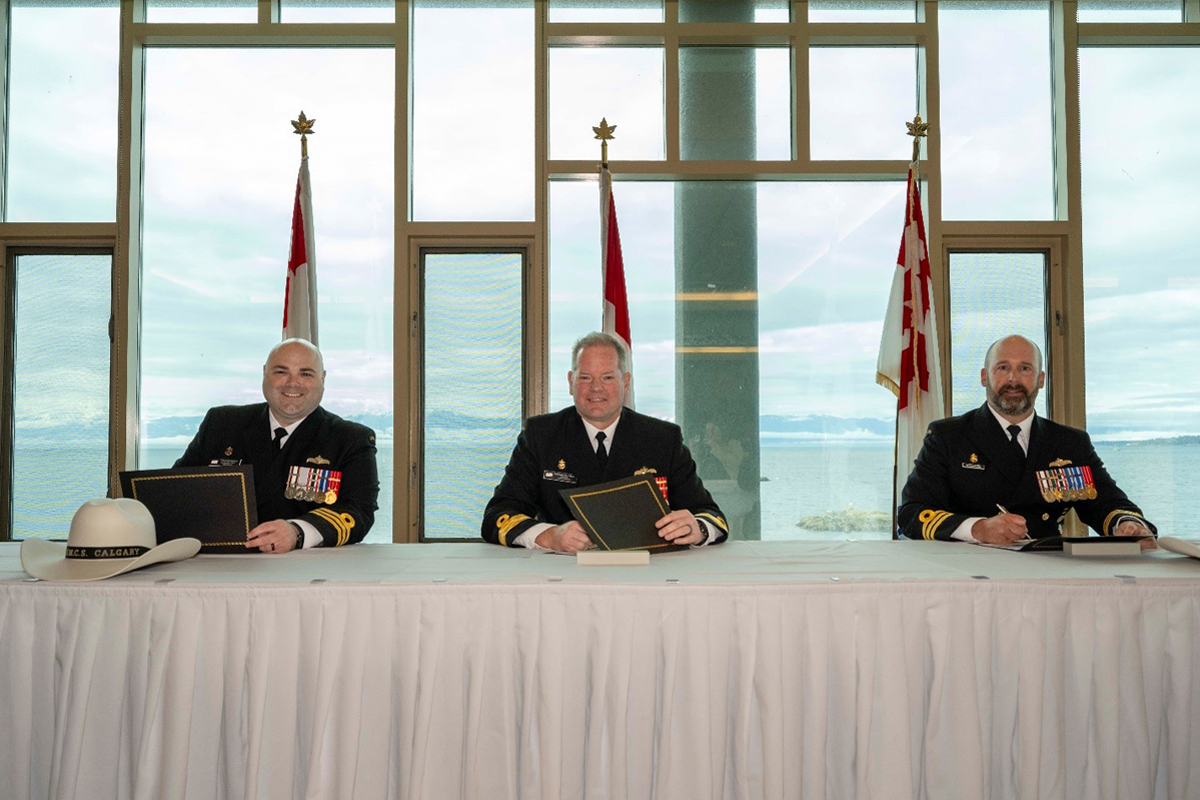 (L-R): Commander (Cdr) Jeremy Samson, outgoing Commanding Officer (CO), Commodore David Mazur, Reviewing Officer, and Cdr Matthew Woodburn, incoming CO, sign the Change of Command papers at the Change of Command Ceremony in the Rainbow Room of the Chief and Petty Officers’ Mess on May 13.