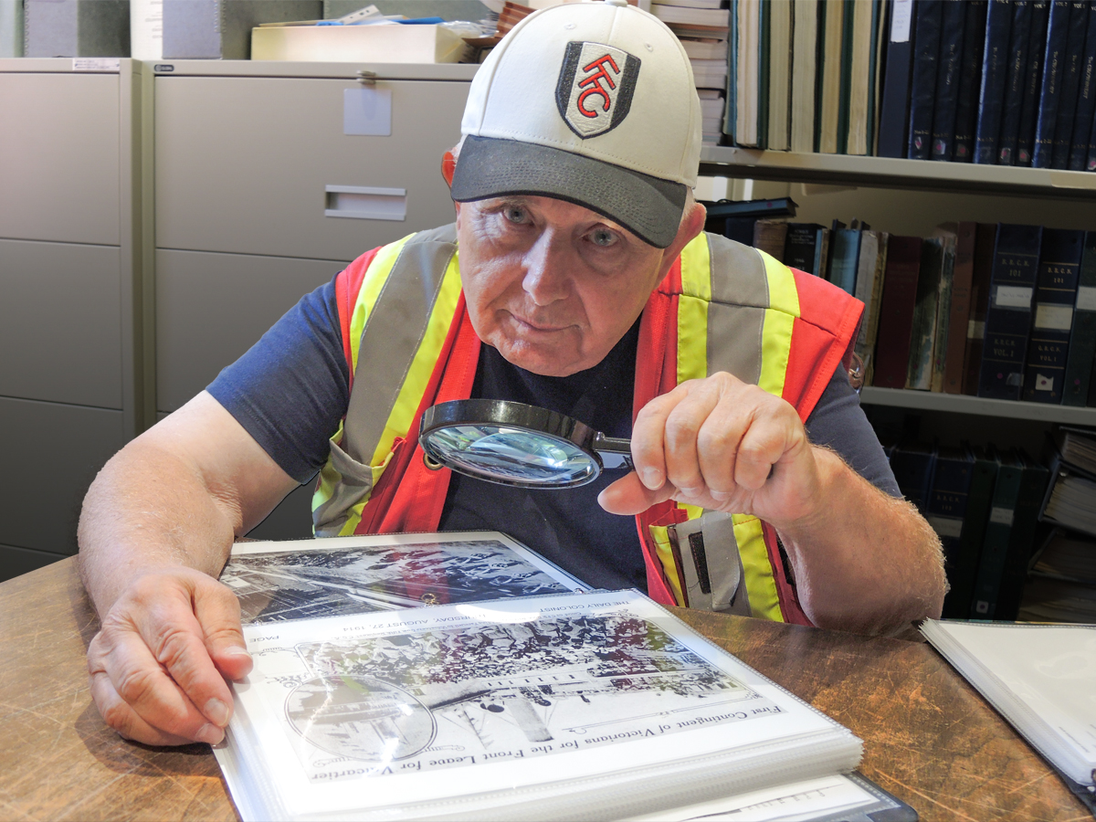 Commissionaire Gary Restell examines a photograph from 1914 depicting a march of Canadian soldiers and 
sailors through Dockyard at the archives of the CFB Esquimalt Naval and Military Museum. 