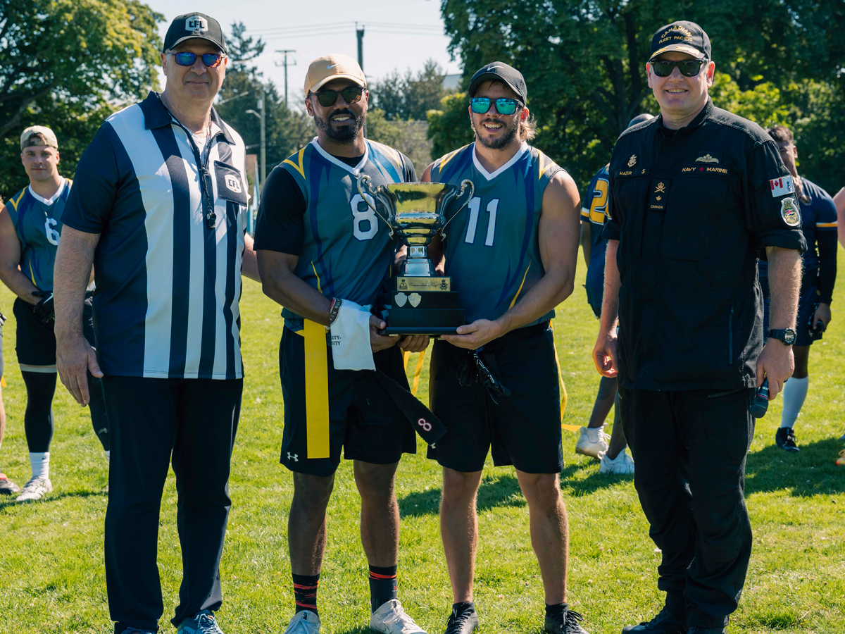 Le commissaire de la Ligue canadienne de football Randy Ambrosie et le Commodore de la Flotte canadienne du Pacifique David Mazur remettent à l’équipe gagnante la Coupe du Commodore lors d’un match de flag football tenu à la Base des Forces canadiennes Esquimalt le 29 août. 